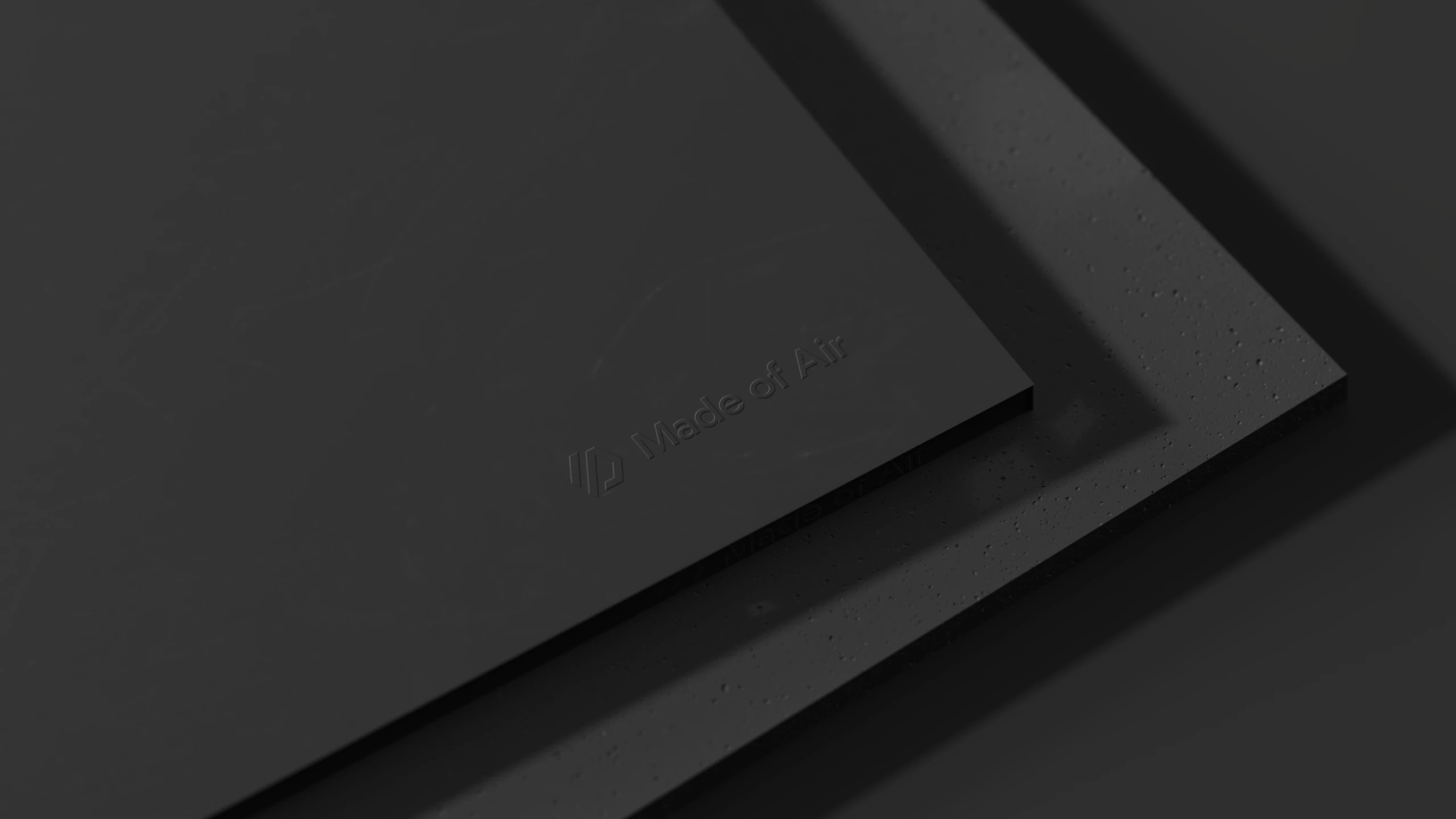 Rendered stack of black panels, the top one debossed with the Made of Air logotype, the one below showing the material's speckled edge
