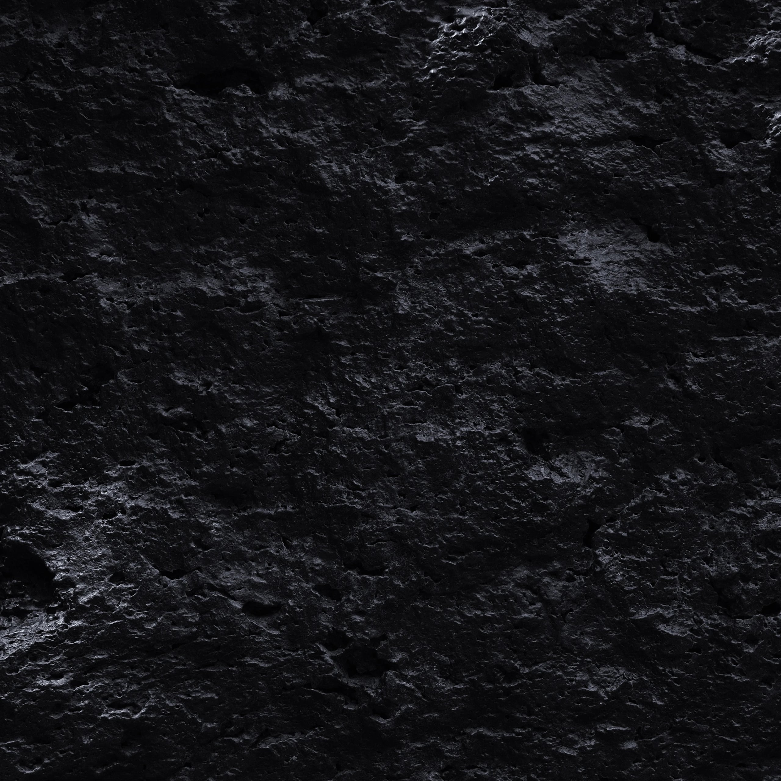 Full-frame texture of rough black charcoal, its surface catching a faint highlight