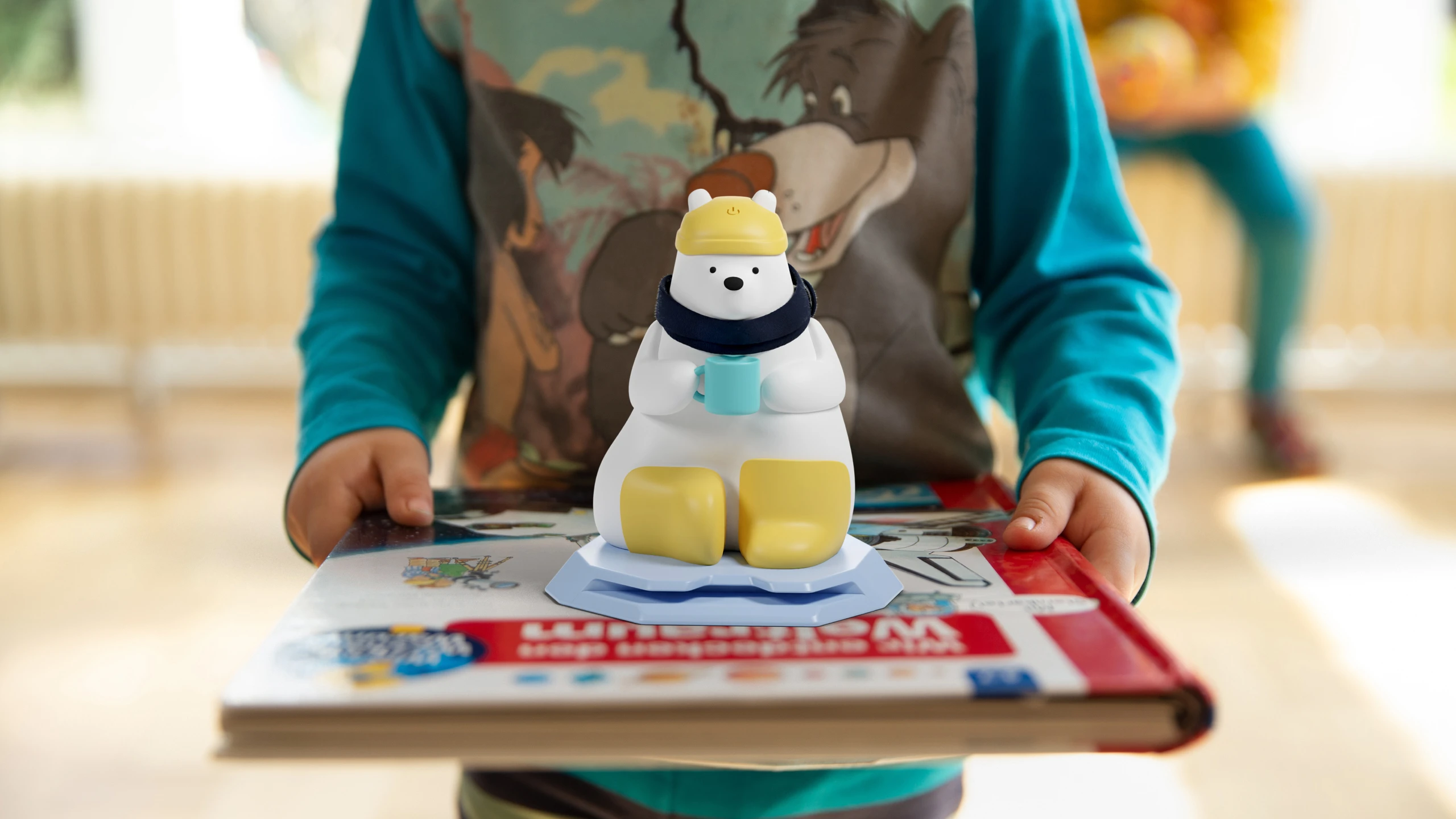 A child holding out a book with the Sami Lesebar clipped to its top edge
