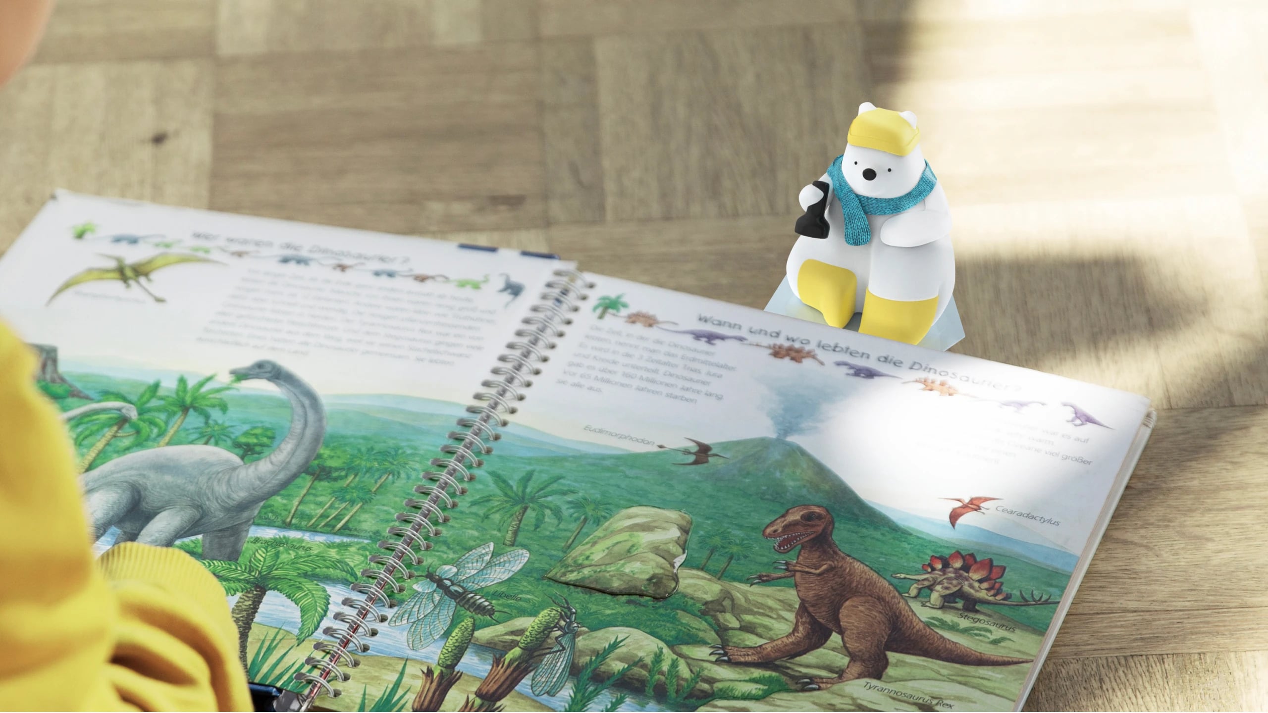 The Milo prototype standing at the top of an open dinosaur book while a child reads the spread