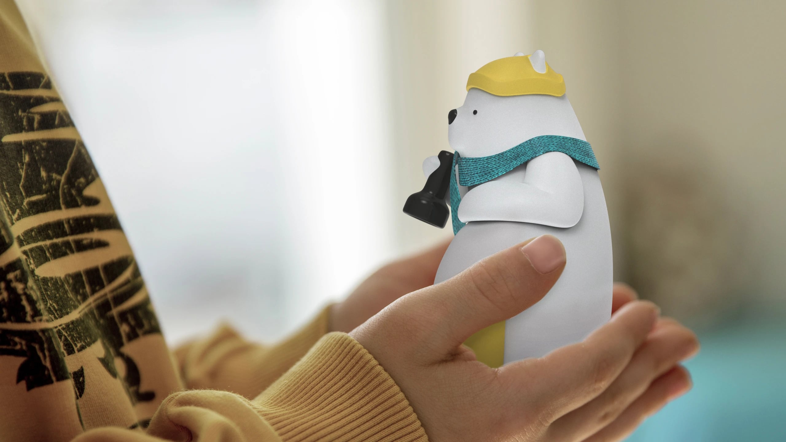 A child holding the Milo prototype in both hands, the polar bear in its yellow cap and knitted teal scarf