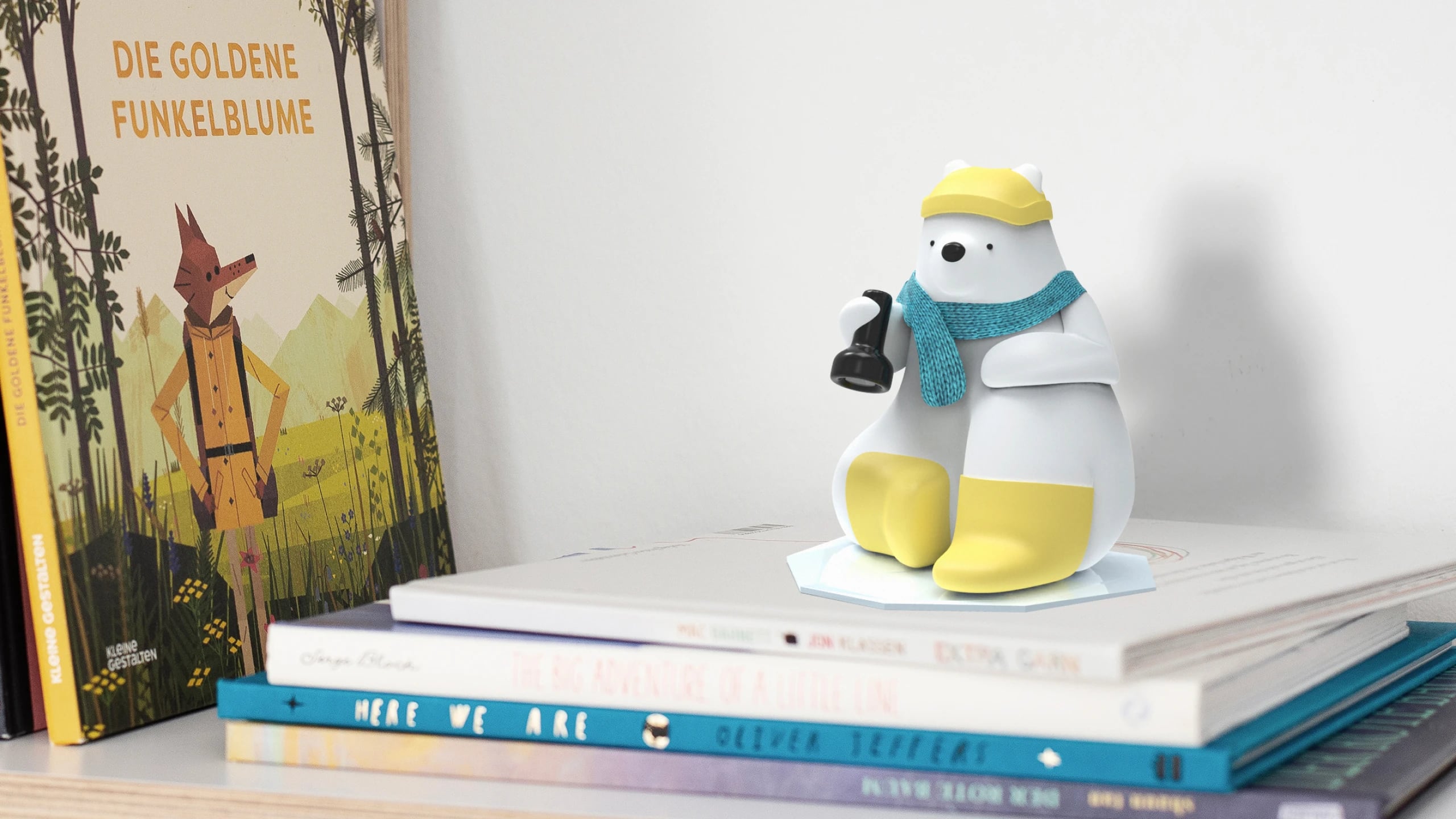 The Milo model sitting on a stack of picture books beside Die goldene Funkelblume, wearing a yellow cap and teal scarf and holding a lamp